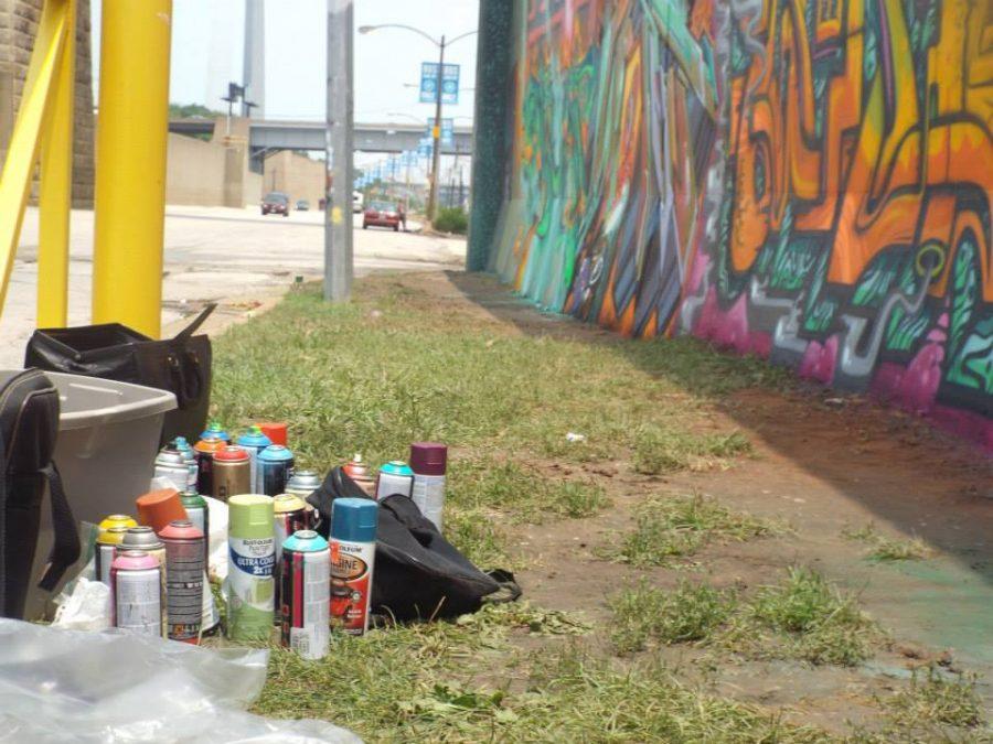 paint supplies sitting along graffiti wall