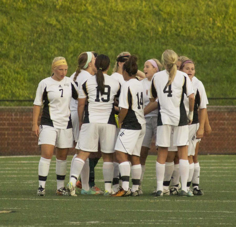 The women's soccer team huddles during a match.