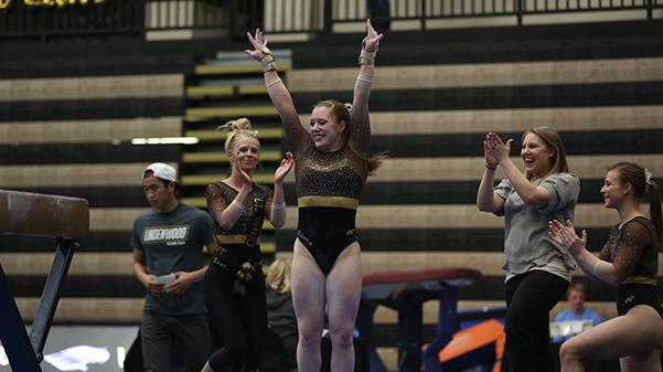 Katey Oswalt and her teammates celebrate at the conclusion of beam her routineduring a a meet at the Hyland Arena.  Photo by Carly Fristoe