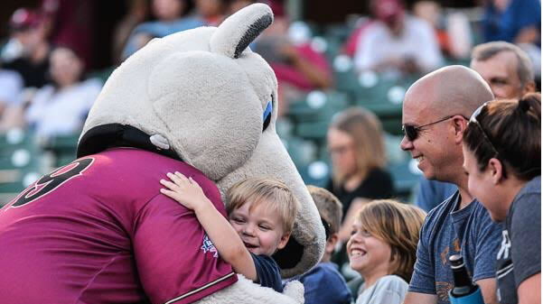 Lindenwood student, Jennifer Wunder, as Ruffy the mascot, hugs a child during a Rascals home game. “It’s just a good feeling all around when you’re around those kids that are just so excited to see you, Wunder said.  Photo by Ricky Rick Photography. 