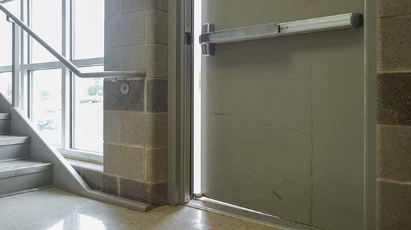 A dorm hall side door propped open, allowing someone to enter from the outside.   Photo illustration by James Tananan Kamnuedkhun