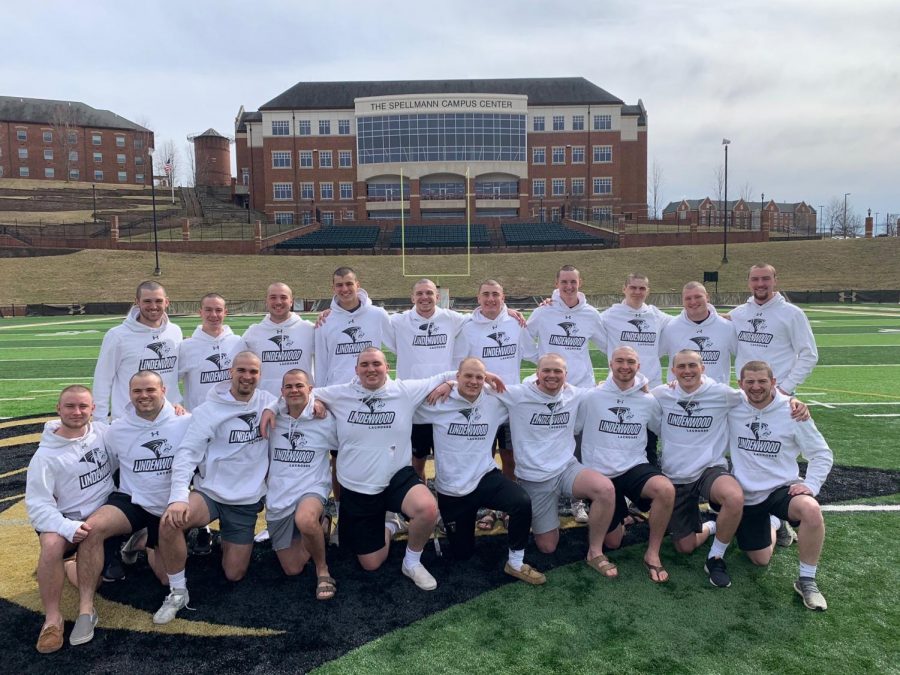The 20 mens lacrosse players who shaved their heads pose in the middle of Hunter Stadiums football field.
