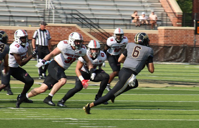 Carter Davis, the Lions quarterback, dodges Austin Peay State University defenders as he goes to the right.