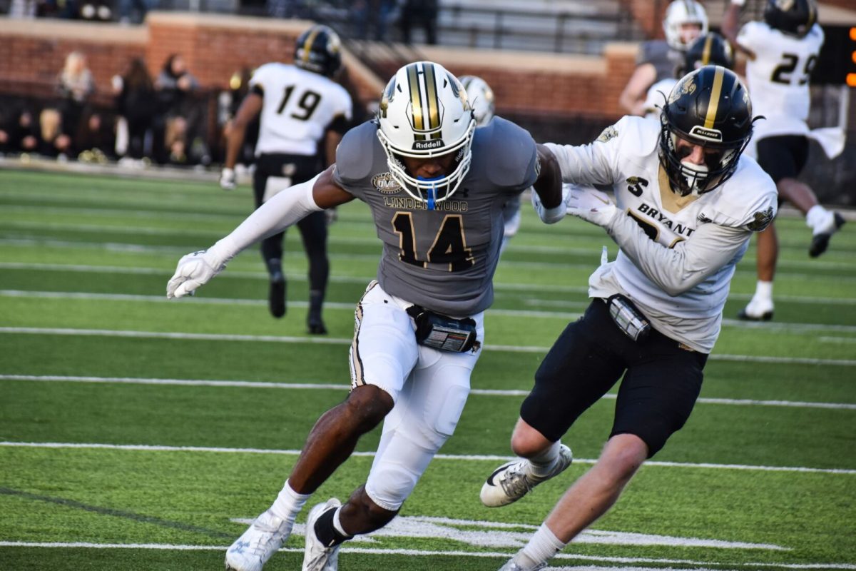 Defensive back Tre Bell skirmishes with a Bryant University defender while running a route. 