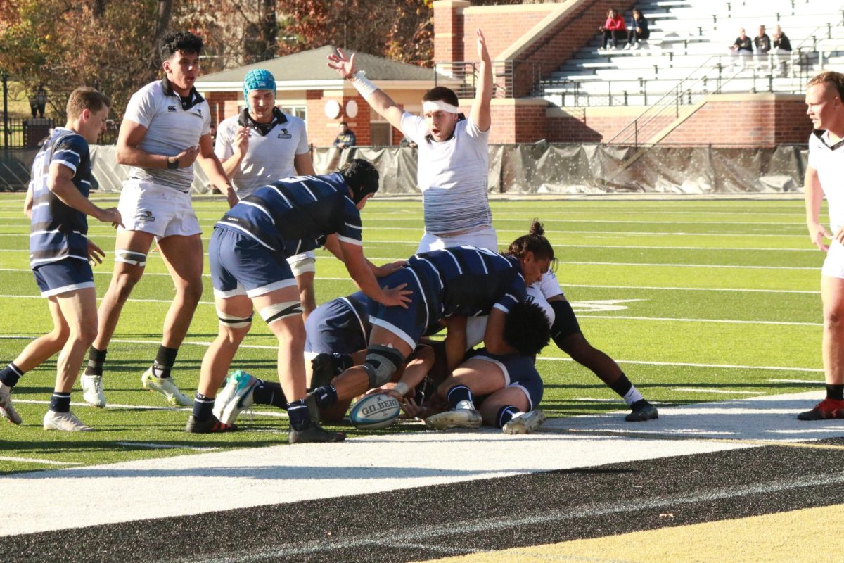Members of the Lindenwood Rugby team celebrate as a skirmish for the ball occurs in front of them. 