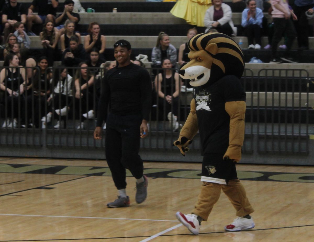 Damarion Williams and Leo the Lion walk onto the Hyland Arena court. 