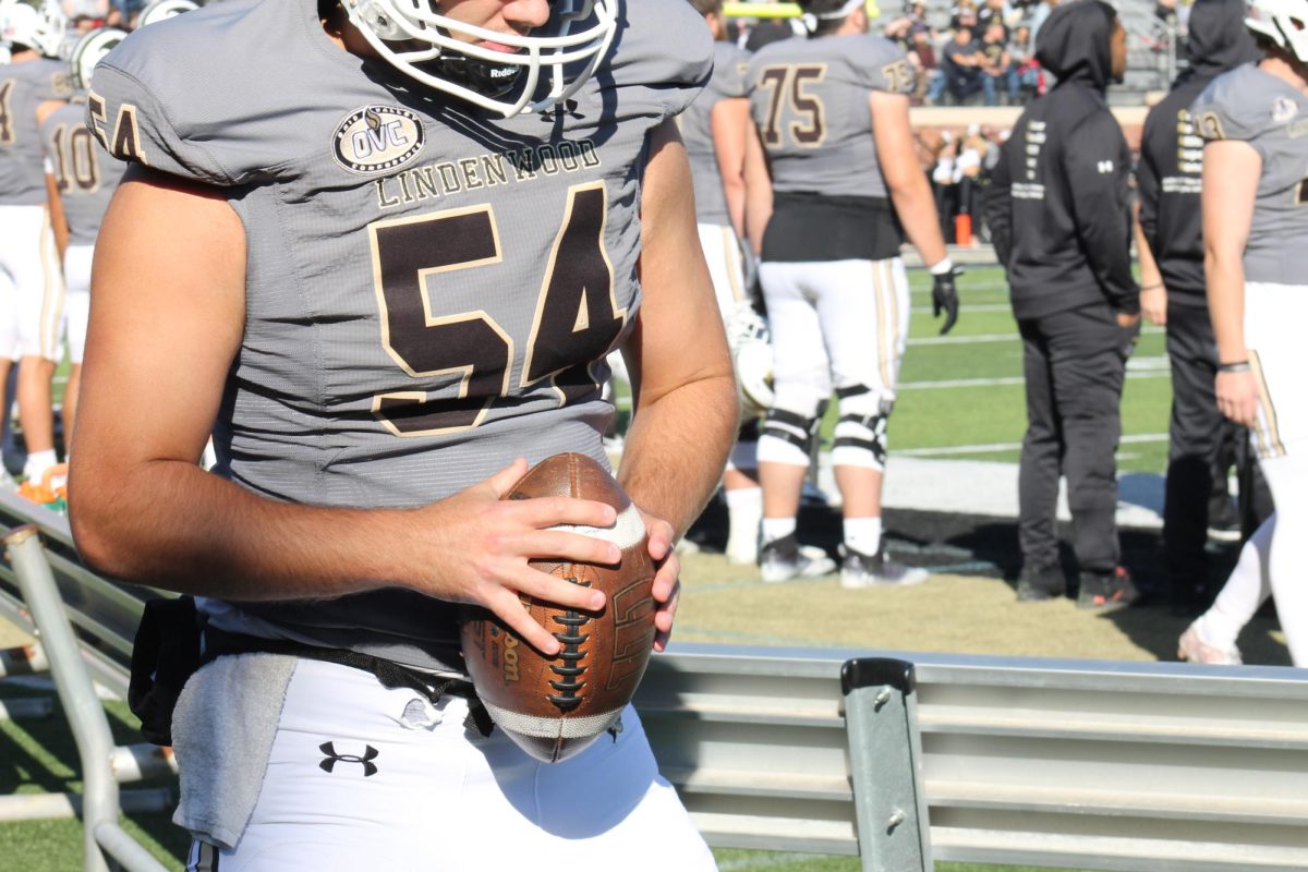 Long snapper Nelson Pipes holds a football on the sidelines.