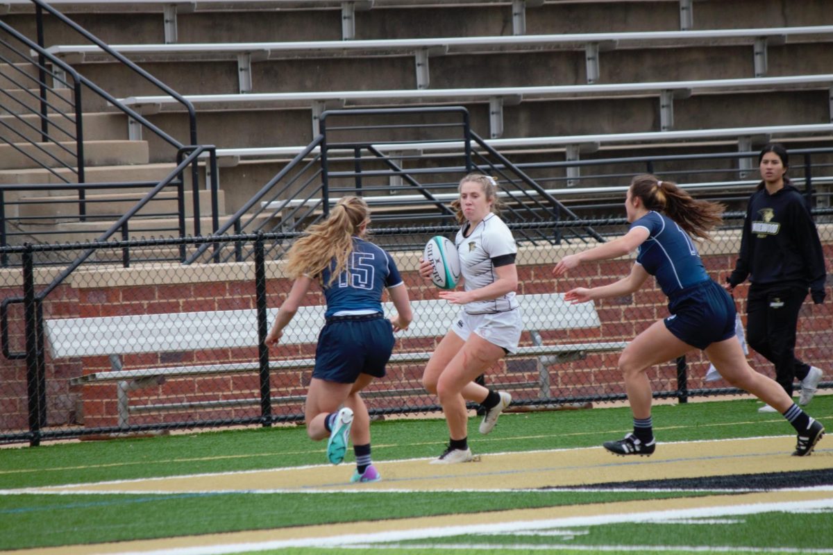 A Lindenwood rugby player is approached by two BYU defenders while attempting to move the ball down field. 