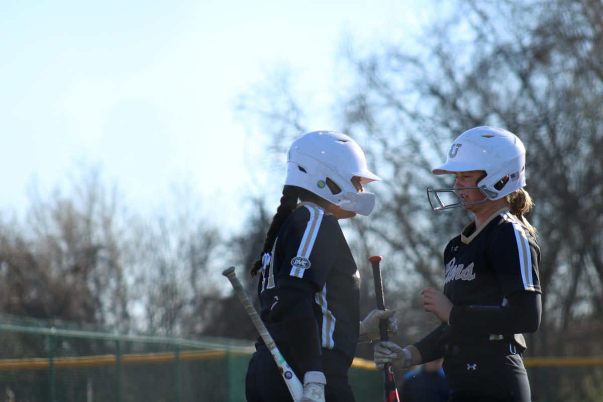 Mya Bethany and Dallis Darnell conversate between at bats against St. Louis University. 