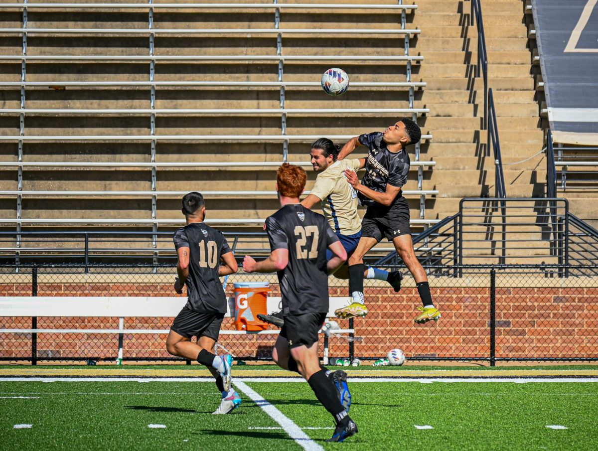 John Gates and a UIS defender leap towards the ball in a game, as Gates teammates Nathan Baker and Henrique Perestrelo look on. 