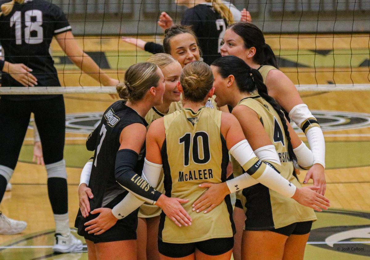 Members of the Lindenwood Lions women's volleyball team huddle after scoring a point in a set against Southern Illinois. 