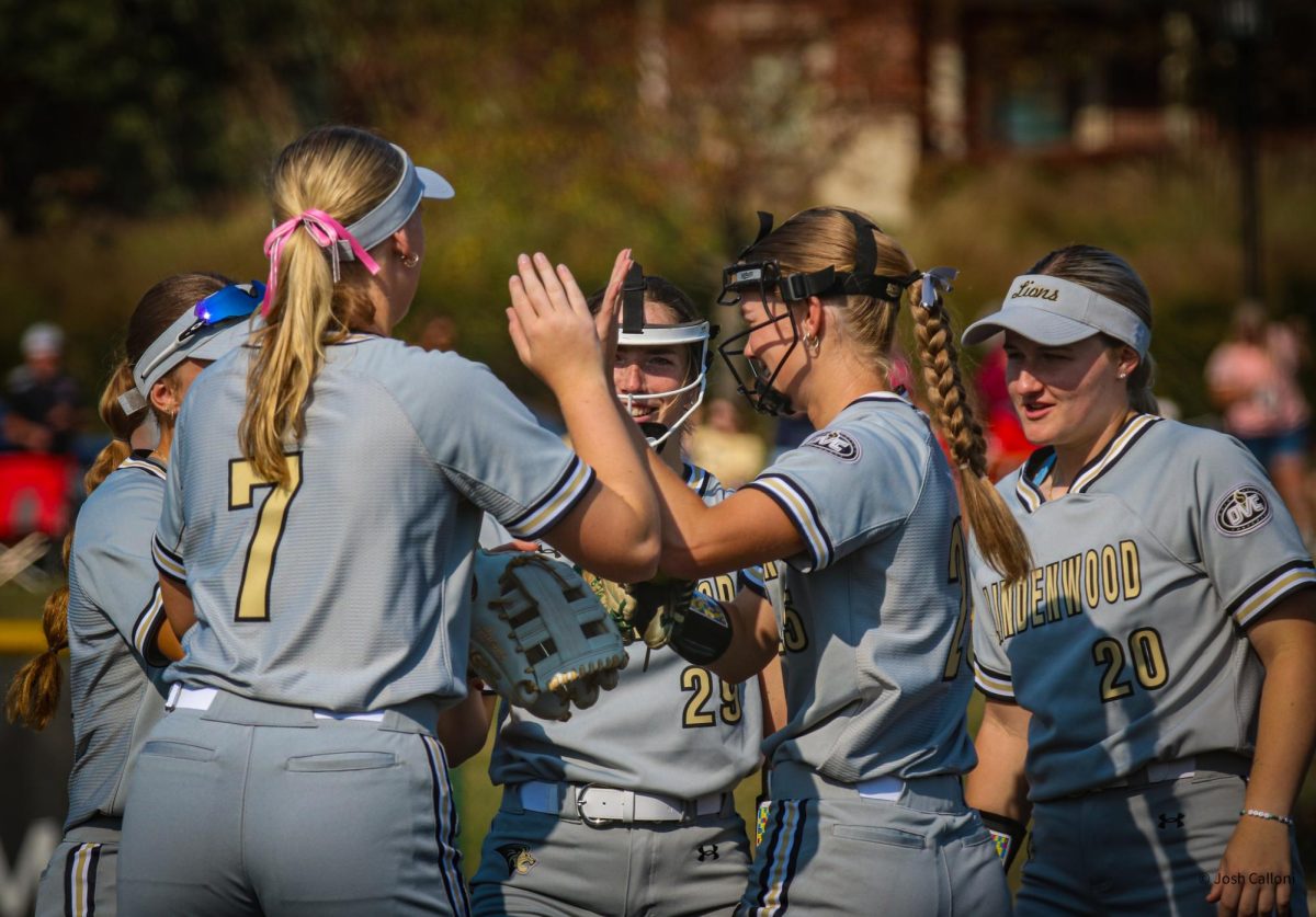 Members of the Lindenwood Lion's softball team greet a new pitcher during an exhibition game against Jefferson College. 